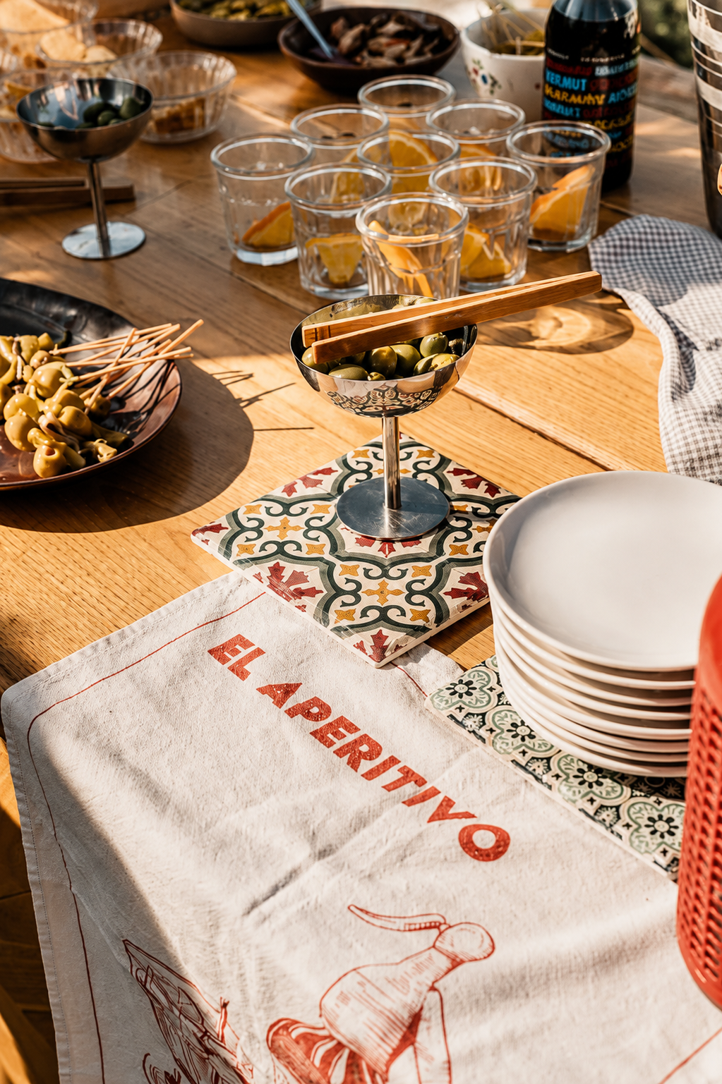 Mesa de aperitivo con vermut, aceitunas y mantel bordado — cóctel de bienvenida en boda en Gandia