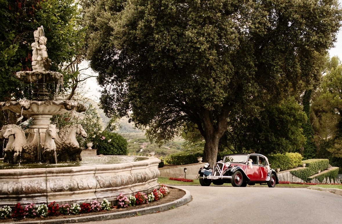 Coche clásico de los novios llegando al banquete junto a la fuente de la finca — fotógrafo de bodas en Gandia